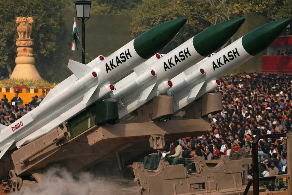 Akash surface-to-air missiles mounted on a launcher vehicle, showcased during a public parade with a large audience in the background.