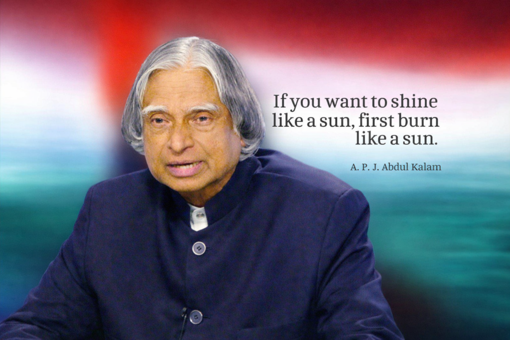 An elderly Indian statesman speaking with an inspirational quote in the background that reads, тАЬIf you want to shine like a sun, first burn like a sun.тАЭ